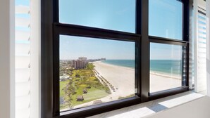 Blick aus einem Fenster auf einen Strand mit einem Golfplatz und Gebäuden in der Ferne.