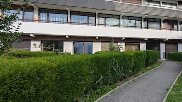 Un immeuble résidentiel à plusieurs étages, doté d’un chemin pavé et de haies bien entretenues.