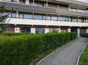 Ein mehrstöckiges Wohngebäude mit gepflastertem Weg und gepflegten Hecken.