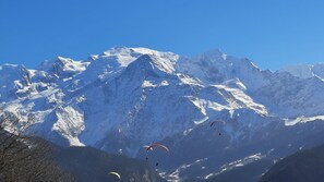 Un paysage montagneux avec des sommets enneigés et des parapentes au premier plan.