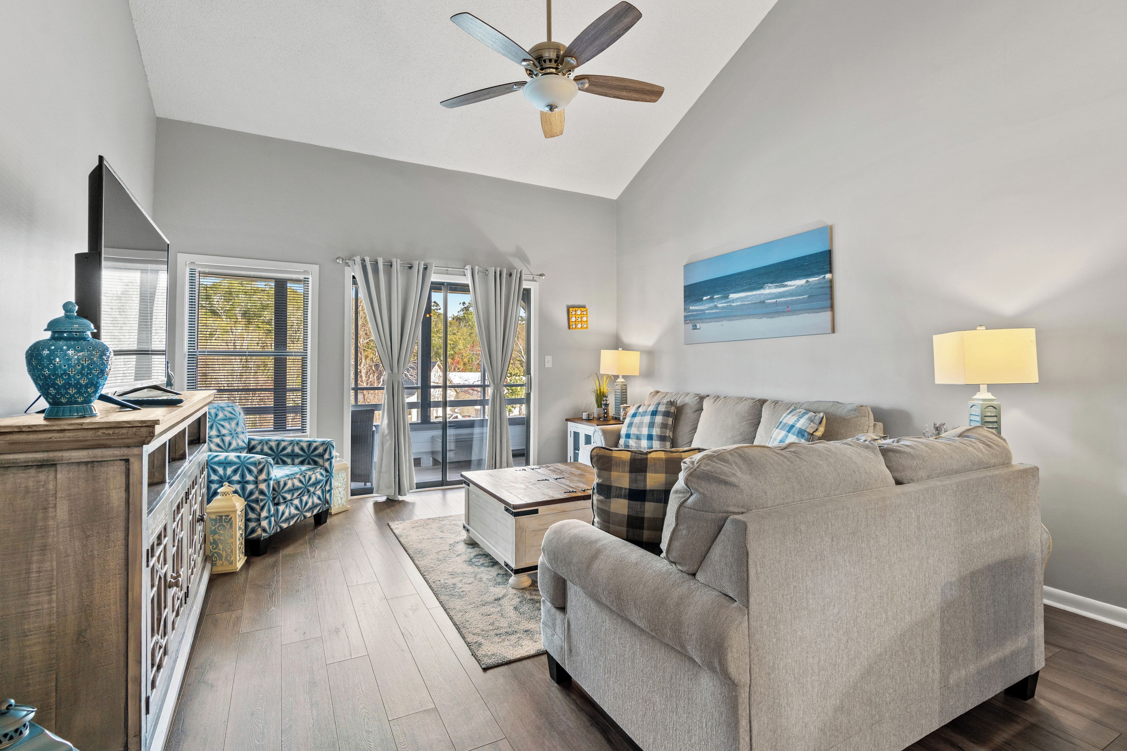 A spacious living room with a sofa, armchairs, a coffee table, and a ceiling fan.