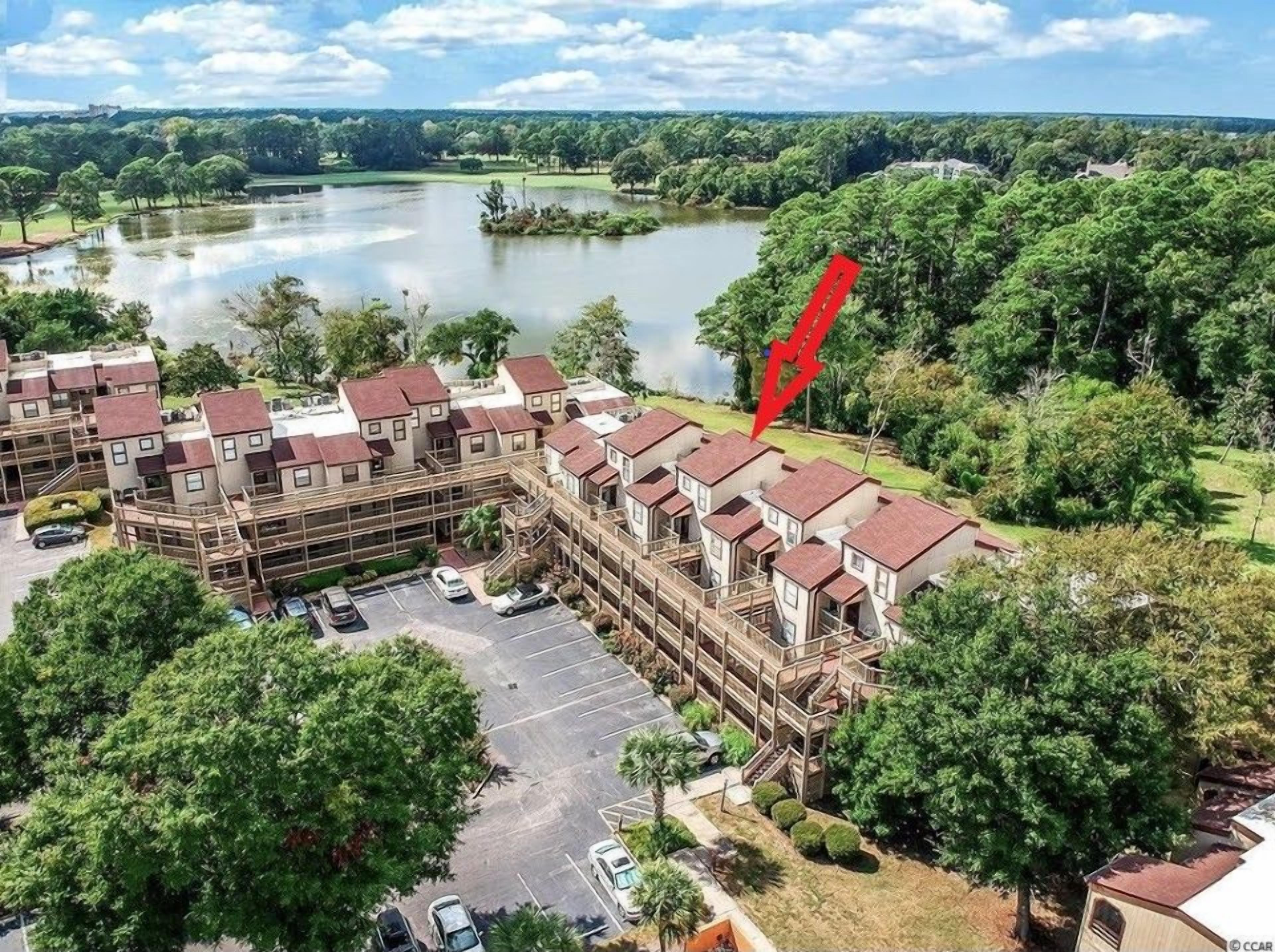 Un edificio residenziale a più piani con un parcheggio e un lago sullo sfondo.