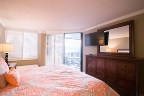 Une chambre avec un lit, une commode, une télévision et un balcon avec vue.