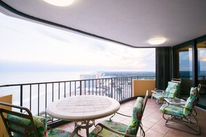 Un balcon avec une table ronde et quatre chaises, offrant une vue sur le paysage urbain et l’océan.
