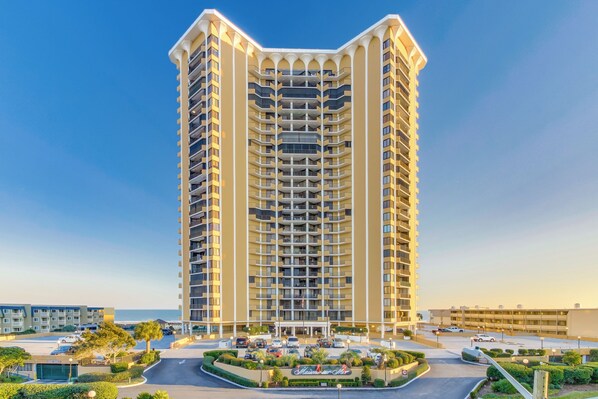 A tall, multi-story hotel with a central courtyard and a view of the sea. - Recently updated condo, 24 hour secured building + Free Attraction Tickets! (Myrtle Beach)
