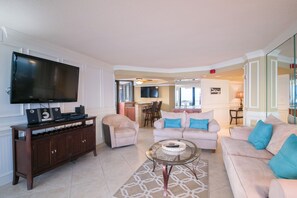 A living room with a flat-screen TV, a wooden entertainment unit, two sofas, and a glass coffee table. - Recently updated condo, 24 hour secured building + Free Attraction Tickets! (Myrtle Beach)