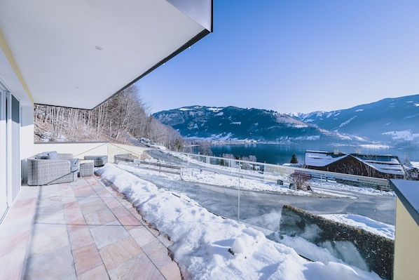 A balcony with a view of snow-covered mountains and a lake.