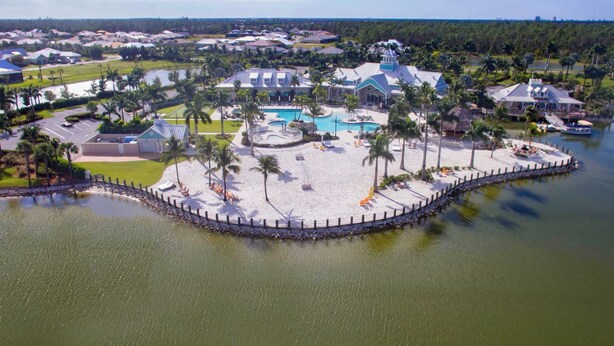 A resort with a central pool, multiple buildings, and a sandy beach area. - Wonderful Pet Friendly Villa in Amenities Filled Naples Reserve (Naples)