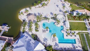 An aerial view of a resort with a large pool, palm trees, and a beach area. - Wonderful Pet Friendly Villa in Amenities Filled Naples Reserve (Naples)