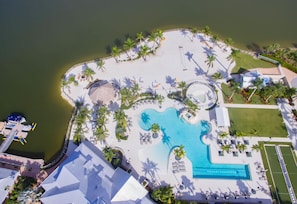 An aerial view of a resort with a large pool, palm trees, and a beach area. - Wonderful Pet Friendly Villa in Amenities Filled Naples Reserve (Naples)