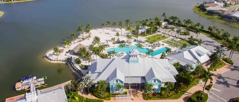 A resort with a large pool, multiple buildings, and a surrounding water body.