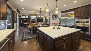 Una cocina moderna con armarios de madera oscura, una isla grande de mármol, electrodomésticos de acero inoxidable y un comedor con chimenea.