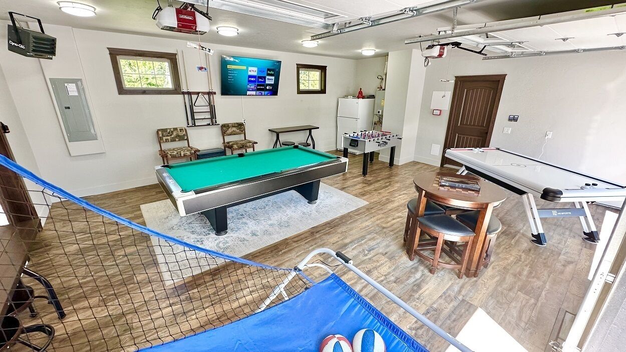 Een kamer met een pooltafel, een tafelvoetbaltafel en een pingpongtafel.