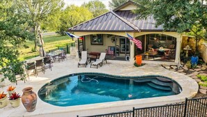 Ein Garten mit Pool, Terrassenmöbeln und einer überdachten Sitzgruppe.