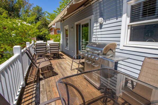 Una terraza con mobiliario exterior, una parrilla y una mesa de vidrio.