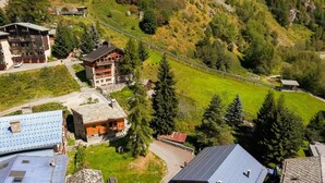 A mountainous area with a ski lift, buildings with balconies, and a green landscape. - Chalet, 50m from ski slopes, view mountain, terrace, fireplace or stove, tv, ski locker, 130m² (Tignes)