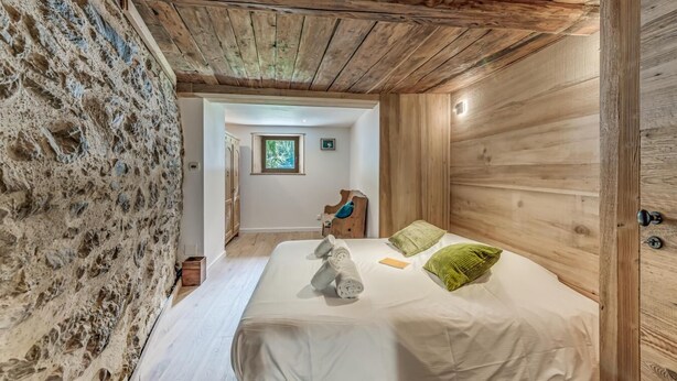 A bedroom with a wooden ceiling, a bed with white bedding, and a wooden wall. - Chalet, 50m from ski slopes, view mountain, terrace, fireplace or stove, tv, ski locker, 130m² (Tignes)