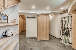 A ski lodge interior with wooden walls, a ski rack, and a helmet on a shelf.