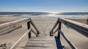 A wooden staircase leading to a sandy beach with a clear view of the ocean. - The Cottage @ Dolphin's Watch Down (Folly Beach)