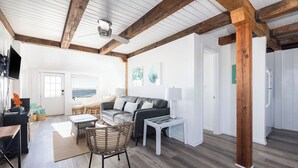 A spacious living area with a wooden ceiling, a sofa set, a coffee table, and a television. - The Cottage @ Dolphin's Watch Down (Folly Beach)