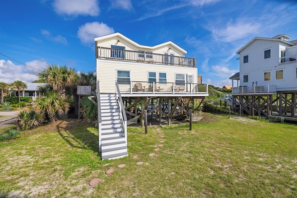 A two-story house with a balcony and a staircase leading to an upper deck.