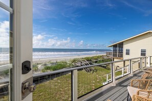 Une propriété située en bord de mer, dotée d’un balcon donnant sur l’océan, d’une terrasse en bois et d’un bâtiment également pourvu d’un balcon.
