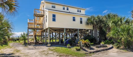 Une maison à deux étages dotée d’une terrasse en bois et d’un escalier menant à un niveau supérieur.