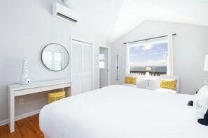 A bedroom with a large bed, a bedside table, a mirror, a window with a view, and a ceiling fan. - "The Retreat" at Dolphin's Watch - Up (Folly Beach)