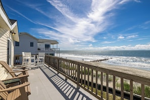 A beachfront property with a wooden deck, white chairs, and a view of the ocean. - "The Retreat" at Dolphin's Watch - Up (Folly Beach)