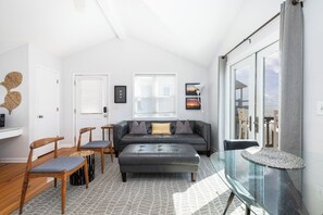 A modern living room with a sofa, chairs, a glass table, and a view of the sea. - "The Retreat" at Dolphin's Watch - Up (Folly Beach)