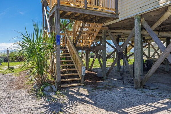 A wooden structure with a staircase leading to a deck, surrounded by natural vegetation.