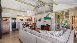 A spacious living area with a large sofa, dining table, and kitchen in the background.