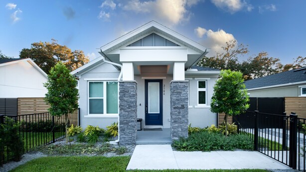 A modern single-story house with a front porch, stone pillars, and a blue door.