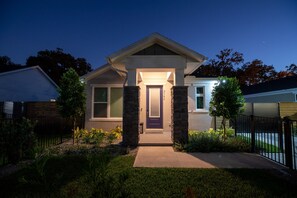 A modern two-story house with a front porch, a well-maintained lawn, and a black metal fence. - Brand New Modern Pet Friendly Zen Home W/ Private Home Theater & Hot Tub! 2 Bedroom Home by RedAwning (Orlando)