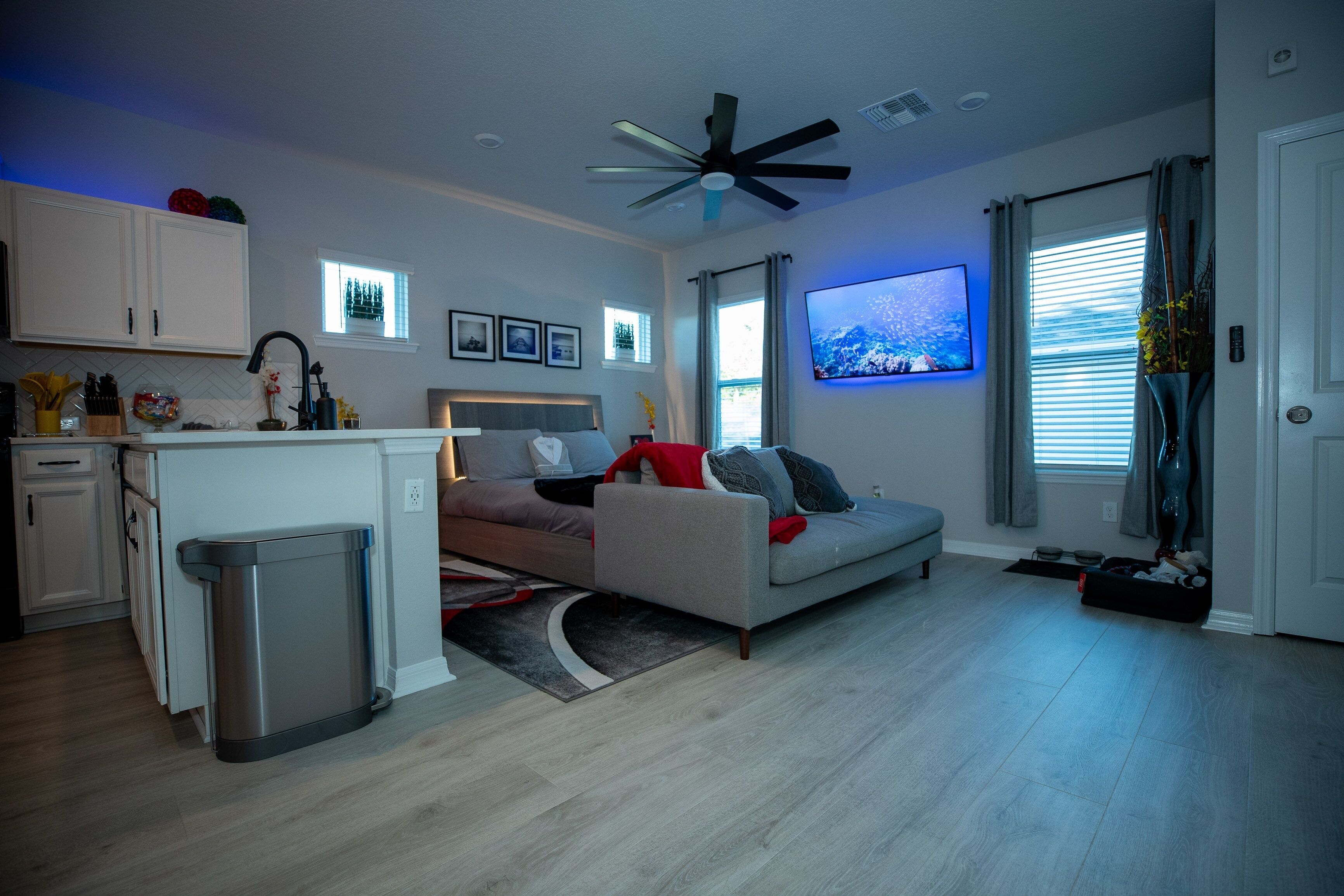 A modern living room with a sofa, a dining area, and a kitchen.