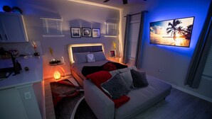 Un dormitorio moderno con una cama, mesitas de noche, un televisor y una mesilla.
