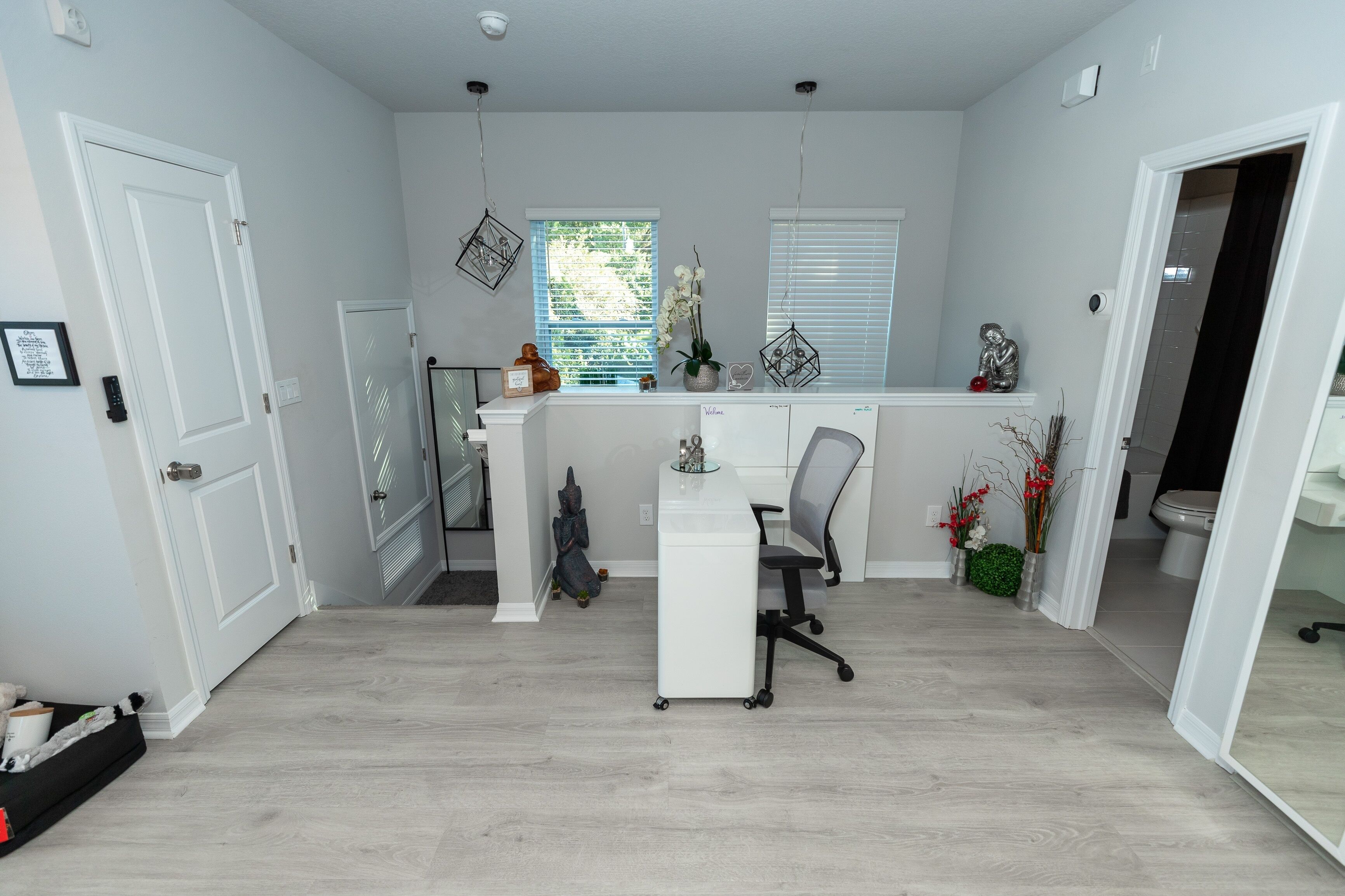 A modern home office with a desk, chair, and two windows.