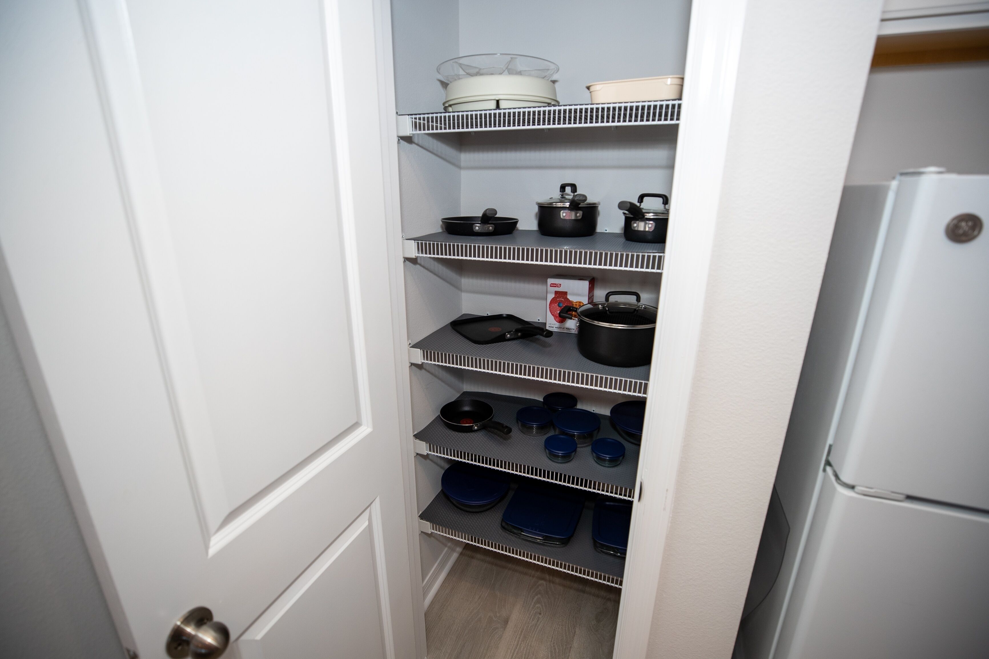 A kitchen pantry with shelves holding cookware and kitchenware.