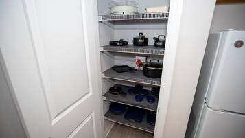 A kitchen pantry with shelves holding cookware and kitchenware.