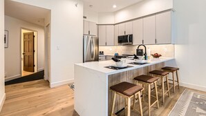 Cozinha moderna com ilha central, eletrodomésticos de aço inoxidável e banquetas.