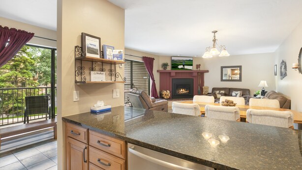 A modern kitchen with granite countertops, a built-in oven, and a dining area with a fireplace.