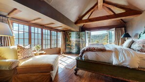 A bedroom with a large bed, a sofa, and a view of the outdoors. - Juniper Ridge 16 5000 sq ft, Grand Chateau at Eagle, Expansive Mountain Views by RedAwning (Mammoth Lakes)