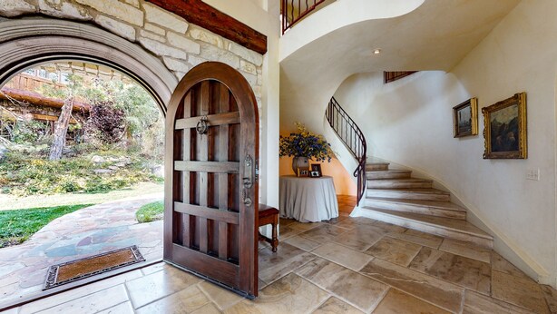 A grand entrance with a wooden door, a stone staircase, and a view of the garden. - Juniper Ridge 16 5000 sq ft, Grand Chateau at Eagle, Expansive Mountain Views by RedAwning (Mammoth Lakes)