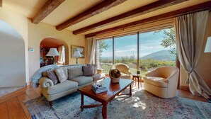 A living room with a sofa, armchairs, a coffee table, and a view of mountains through large windows. - Juniper Ridge 16 5000 sq ft, Grand Chateau at Eagle, Expansive Mountain Views by RedAwning (Mammoth Lakes)