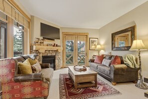 A living room with a fireplace, two sofas, a coffee table, and a television. - Spacious, Mountain Chic, Close to Ski Lift 1 bedroom - TM316 by Redawning (Copper Mountain)