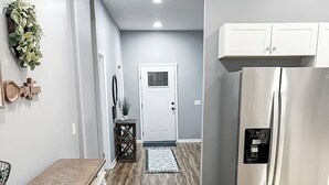 Eine moderne Küche mit Holzboden, einem Edelstahlkühlschrank und einem Essbereich mit Barhocker.