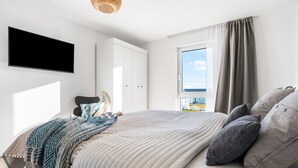Une chambre moderne avec un grand lit, une armoire, une télévision et une fenêtre avec des rideaux.