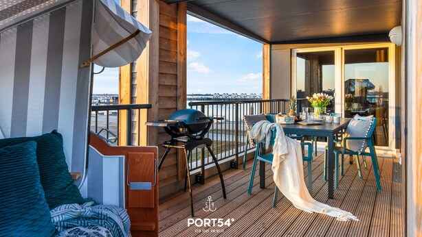 Une terrasse avec un barbecue, des sièges et une vue sur l’eau.