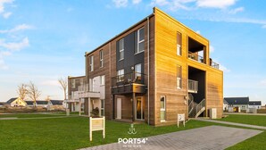Un bâtiment moderne à deux étages, doté d’une façade en bois, d’un balcon et d’un escalier menant à l’étage supérieur.