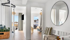 A modern living room with a white sofa, a round mirror, and a basket of fruit. - StrandLoft - Infrared sauna, fireplace, balcony, beach chair, Baltic Sea view (Olpenitz)